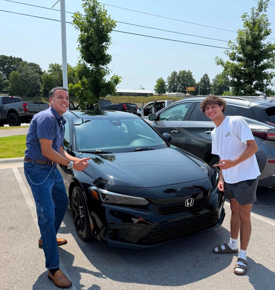 Mario with a client and his new black sedan on the lot